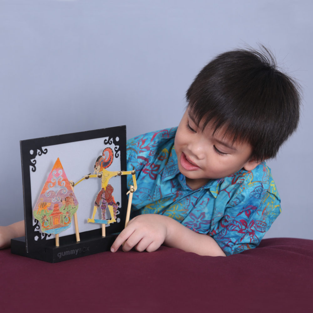 young boy admiring self-made Indonesian wayang kulit